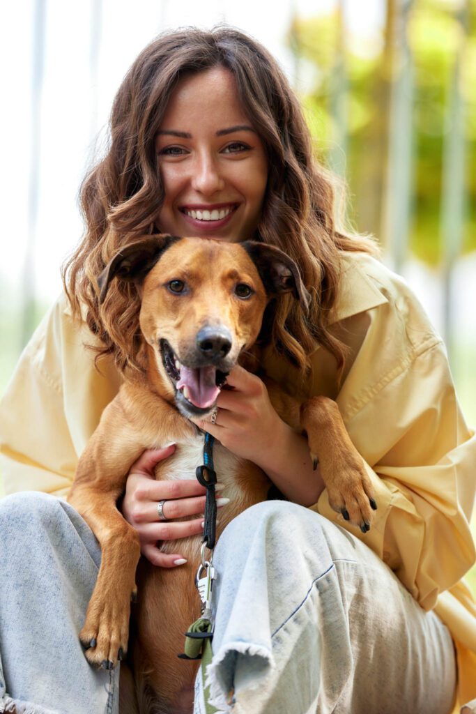 Happy lady holding her brown dog while waiting on her veterinarian.